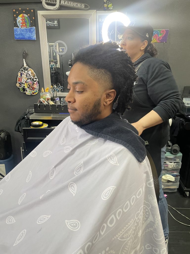 Young man getting dreadlocks in barbershop