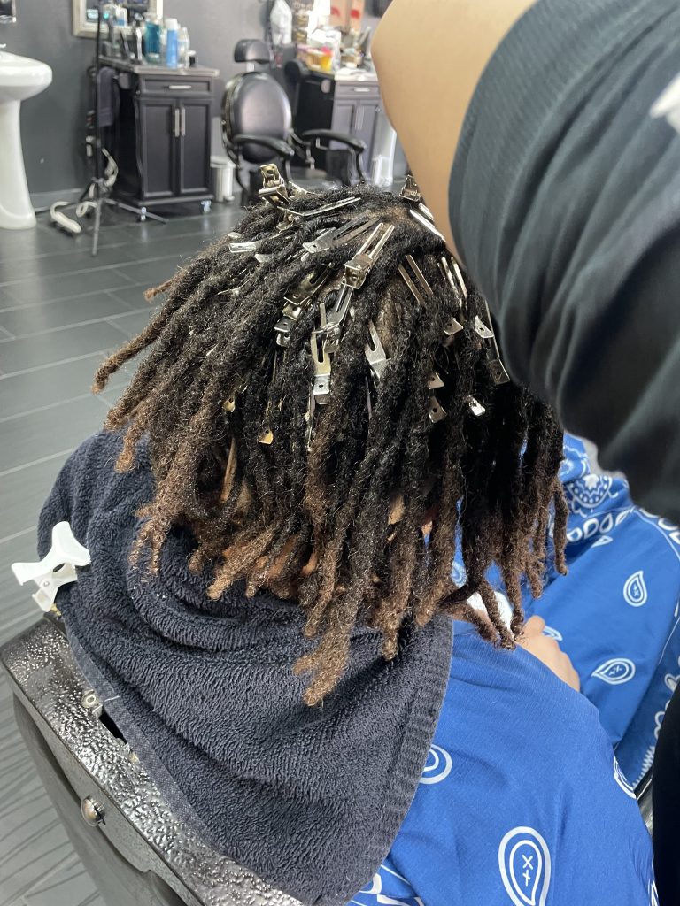 Man getting dreadlocks tended in barbershop